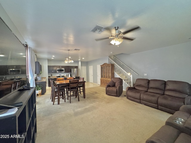 living room with stairs, ceiling fan with notable chandelier, light colored carpet, and visible vents