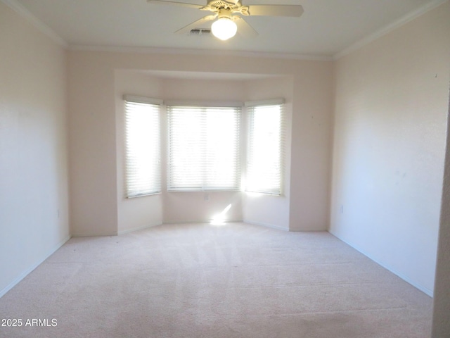 spare room with crown molding, ceiling fan, and light carpet