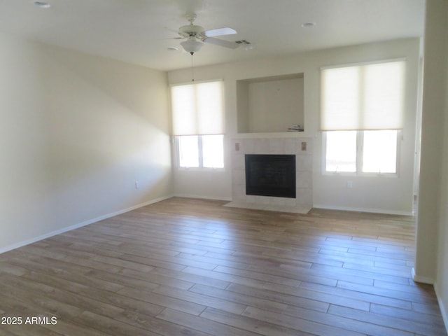 unfurnished living room featuring ceiling fan, light hardwood / wood-style floors, and a tile fireplace