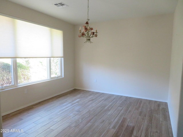 unfurnished room featuring light hardwood / wood-style floors and a chandelier