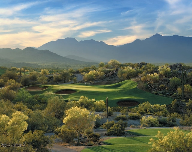 view of property's community with a mountain view, view of golf course, and a lawn