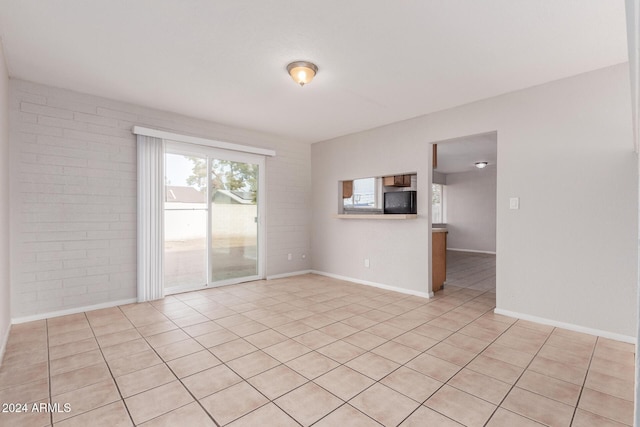 unfurnished room featuring light tile patterned floors and brick wall