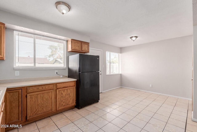 kitchen featuring a wealth of natural light, black refrigerator, and light tile patterned floors