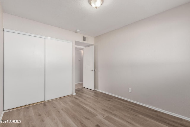 unfurnished bedroom with light hardwood / wood-style flooring and a closet