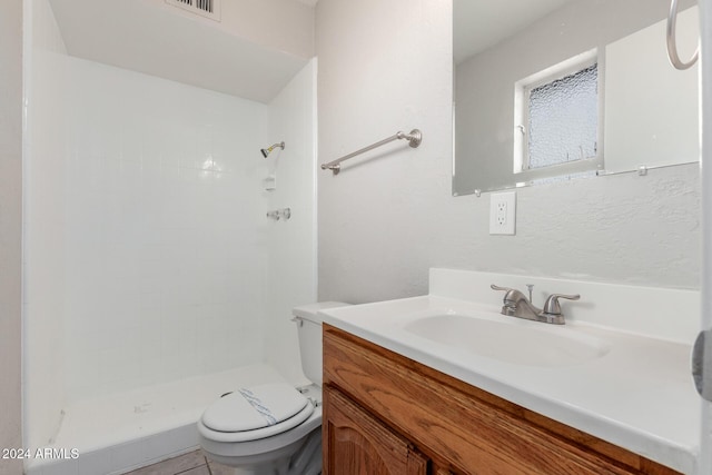 bathroom with a tile shower, tile patterned flooring, vanity, and toilet