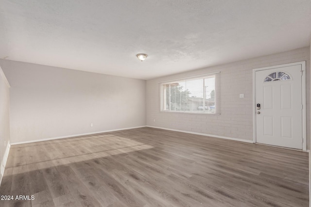 foyer entrance featuring brick wall, a textured ceiling, and hardwood / wood-style flooring