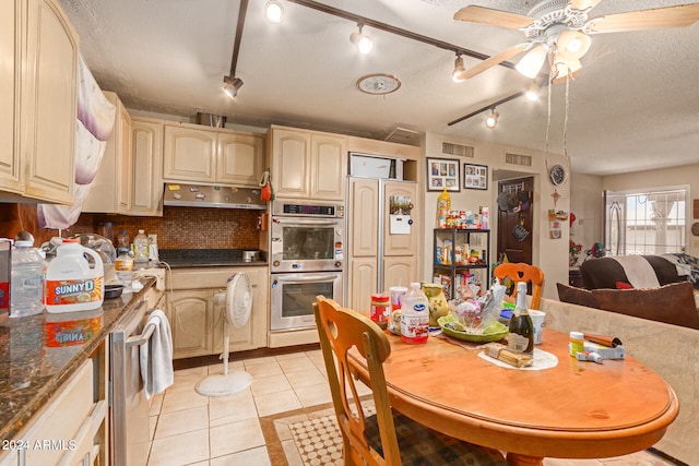 kitchen featuring a textured ceiling, light tile patterned floors, stainless steel double oven, rail lighting, and ceiling fan