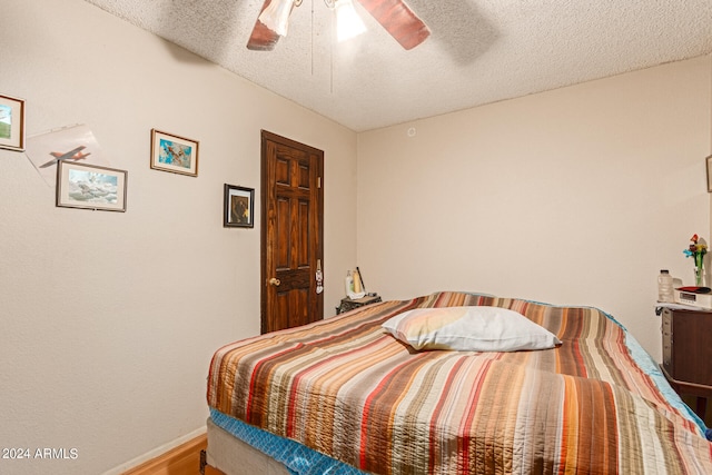 bedroom featuring ceiling fan, hardwood / wood-style flooring, and a textured ceiling