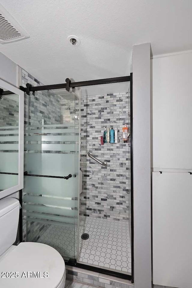 bathroom with visible vents, a stall shower, toilet, and a textured ceiling
