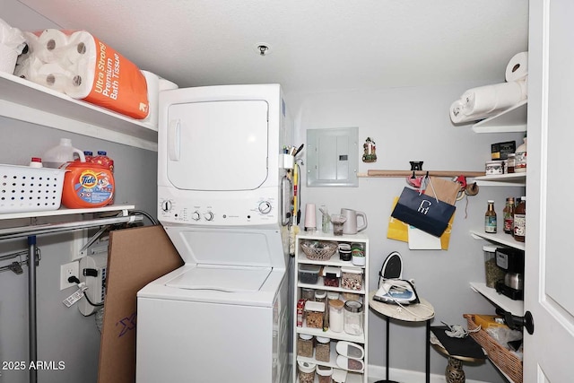 laundry room with electric panel, stacked washer / drying machine, and laundry area