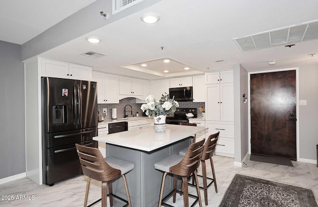 kitchen with black appliances, marble finish floor, a breakfast bar area, and baseboards
