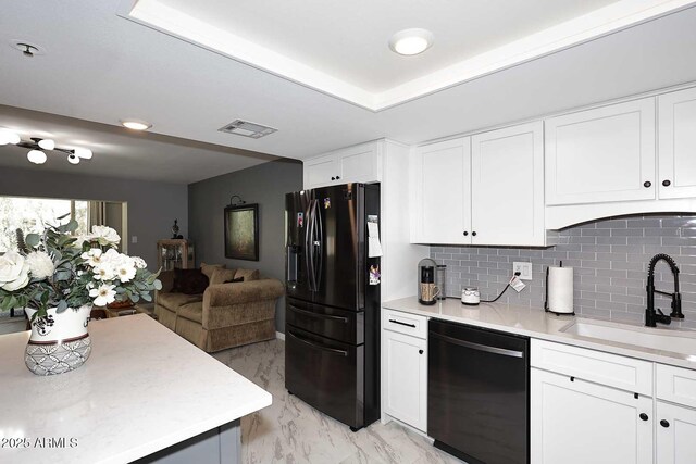 kitchen featuring black fridge with ice dispenser, light countertops, a sink, visible vents, and dishwashing machine