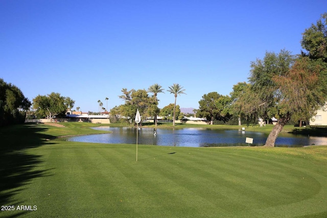view of property's community with a yard, golf course view, and a water view