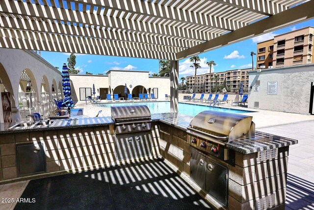 view of patio with a grill, a community pool, a pergola, and exterior kitchen