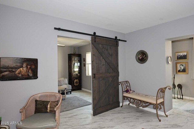 living area featuring marble finish floor, a barn door, and baseboards