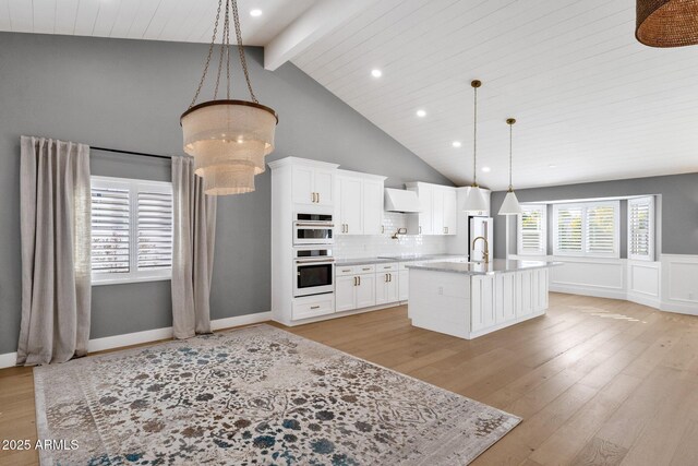 9136 N 81st St, Scottsdale, AZ 85258 - kitchen with white cabinetry, hanging light fixtures, light hardwood / wood-style flooring, double oven, and a kitchen island with sink