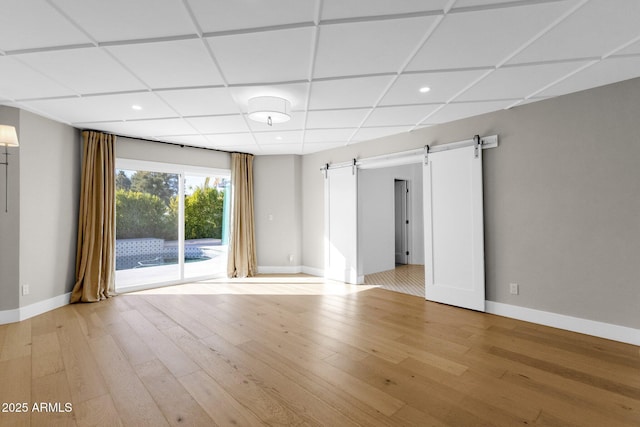 9136 N 81st St, Scottsdale, AZ 85258 - unfurnished room featuring a barn door, a paneled ceiling, and light wood-type flooring