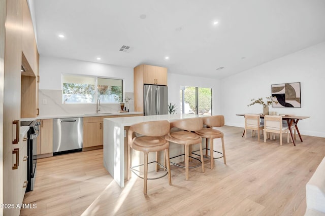 kitchen featuring sink, backsplash, light hardwood / wood-style flooring, and stainless steel appliances