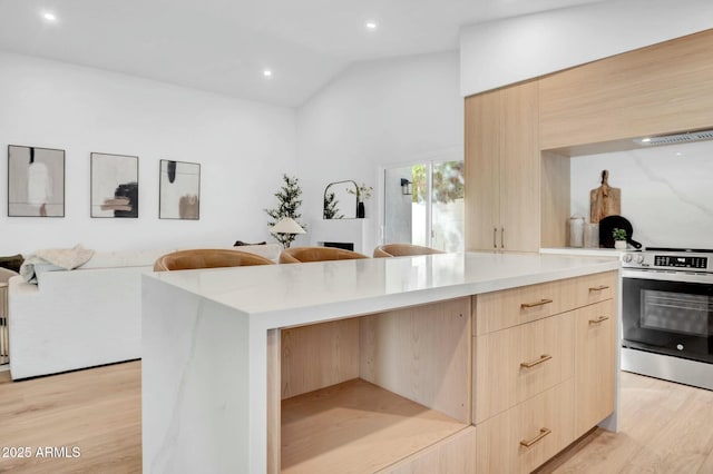 kitchen featuring lofted ceiling, light wood-type flooring, light brown cabinets, a kitchen island, and stainless steel electric stove