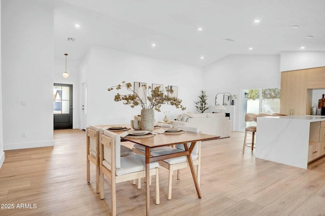 dining room with high vaulted ceiling and light wood-type flooring