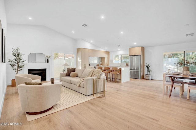 living room featuring lofted ceiling and light hardwood / wood-style floors