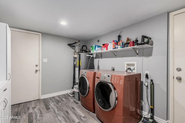 washroom with washer and dryer, water heater, light wood finished floors, baseboards, and laundry area