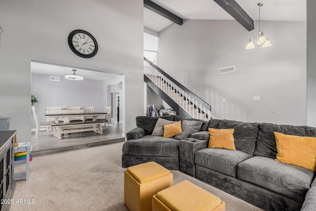 carpeted living room featuring visible vents, a chandelier, beamed ceiling, stairs, and high vaulted ceiling