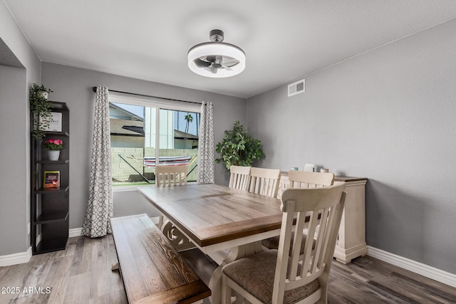 dining space with visible vents, baseboards, and wood finished floors