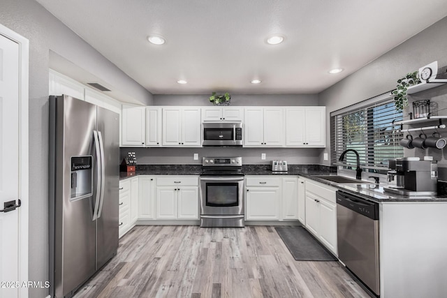 kitchen featuring a sink, light wood-type flooring, appliances with stainless steel finishes, and white cabinets