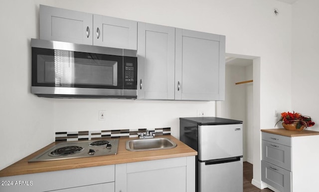 kitchen with appliances with stainless steel finishes, hardwood / wood-style floors, sink, and gray cabinetry