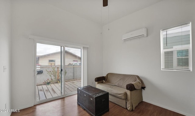 sitting room with a wall unit AC and dark wood-type flooring