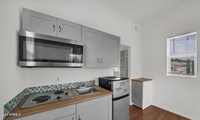 kitchen featuring refrigerator, electric cooktop, dark hardwood / wood-style flooring, gray cabinets, and sink