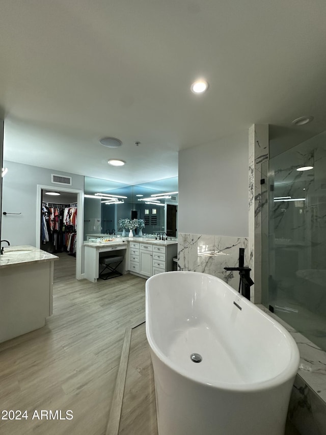 2311 E Colter St, Phoenix, AZ 85016 - full bathroom featuring two vanities, a shower stall, a spacious closet, a soaking tub, and wood finished floors