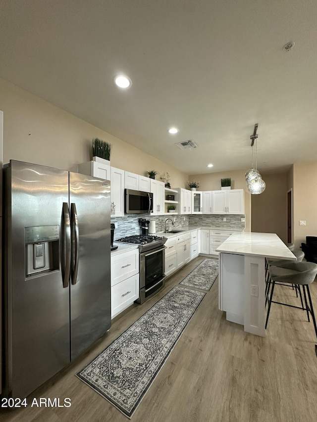 2311 E Colter St, Phoenix, AZ 85016 - kitchen with stainless steel appliances, a sink, light wood-type flooring, tasteful backsplash, and white cabinetry