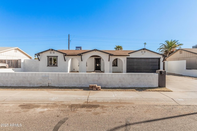 view of front of house with a fenced front yard, driveway, an attached garage, and stucco siding