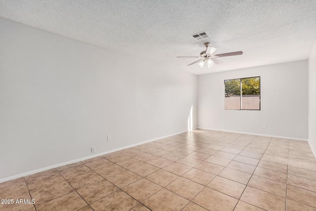 empty room with a ceiling fan, light tile patterned floors, a textured ceiling, and baseboards