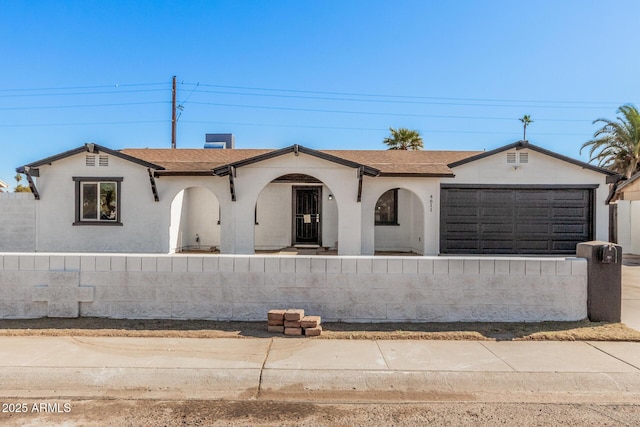 view of front of house with a fenced front yard, a garage, and roof with shingles