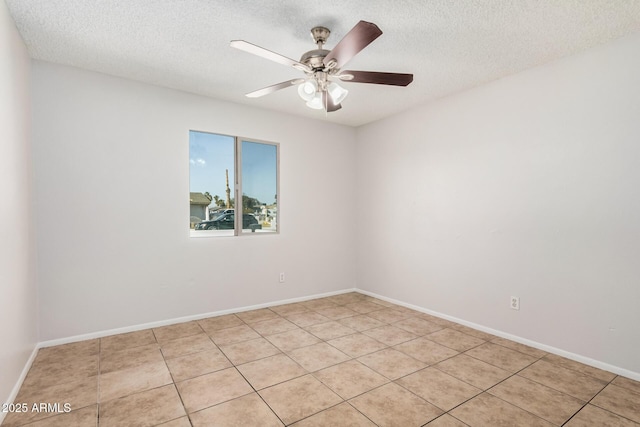 unfurnished room with a textured ceiling, a ceiling fan, light tile patterned floors, and baseboards