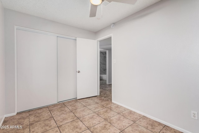 unfurnished bedroom featuring light tile patterned floors, a closet, a ceiling fan, and baseboards