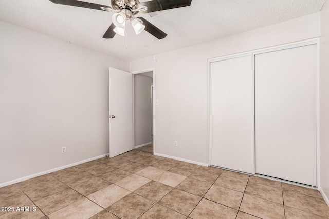 unfurnished bedroom featuring a closet, a ceiling fan, light tile patterned floors, baseboards, and a textured ceiling