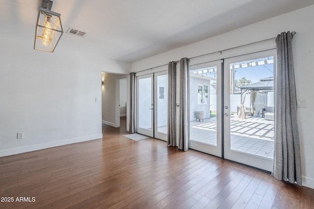 spare room with french doors, baseboards, visible vents, and wood finished floors