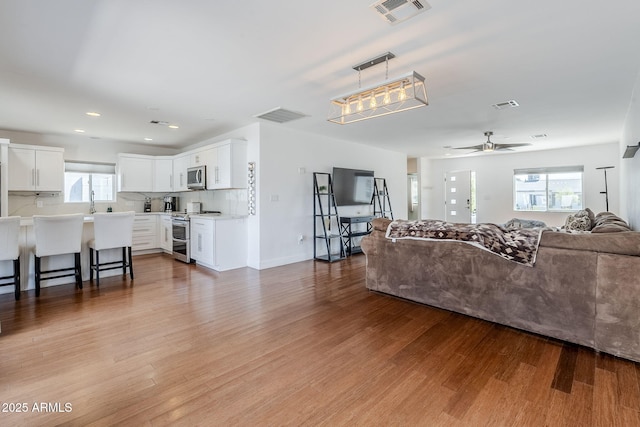 living room featuring visible vents, recessed lighting, a ceiling fan, and wood finished floors