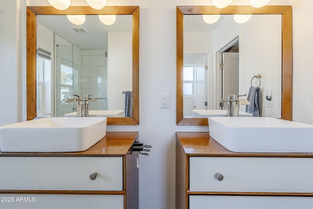 bathroom with visible vents, vanity, and walk in shower