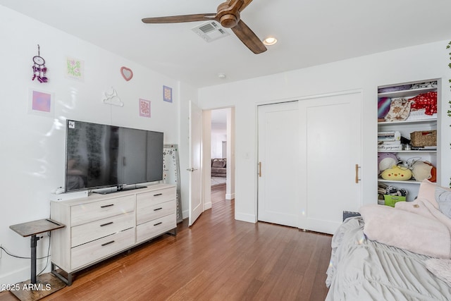 bedroom with visible vents, a ceiling fan, wood finished floors, a closet, and baseboards