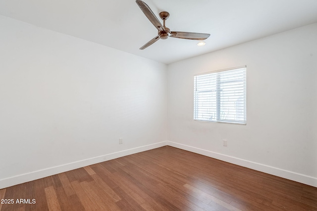 empty room featuring baseboards, wood finished floors, and a ceiling fan