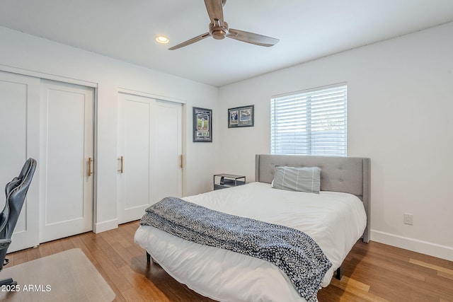 bedroom with two closets, ceiling fan, baseboards, recessed lighting, and wood finished floors