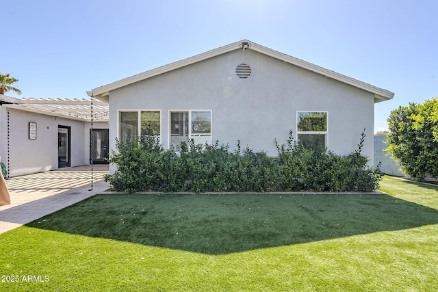 rear view of house featuring stucco siding, a patio, and a yard