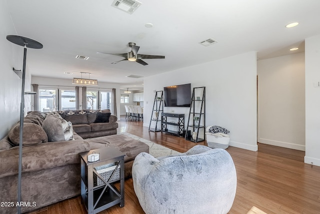 living room featuring wood finished floors, visible vents, and baseboards