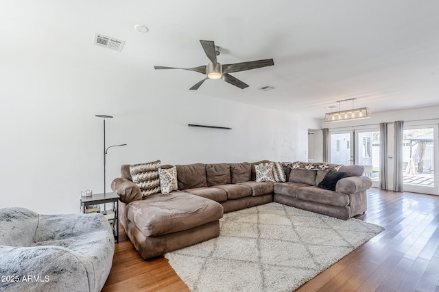 living room featuring a ceiling fan, wood finished floors, and visible vents