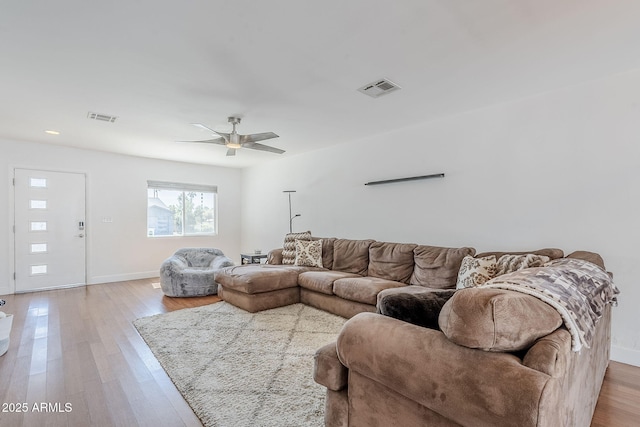 living room with baseboards, visible vents, a ceiling fan, and light wood-style floors